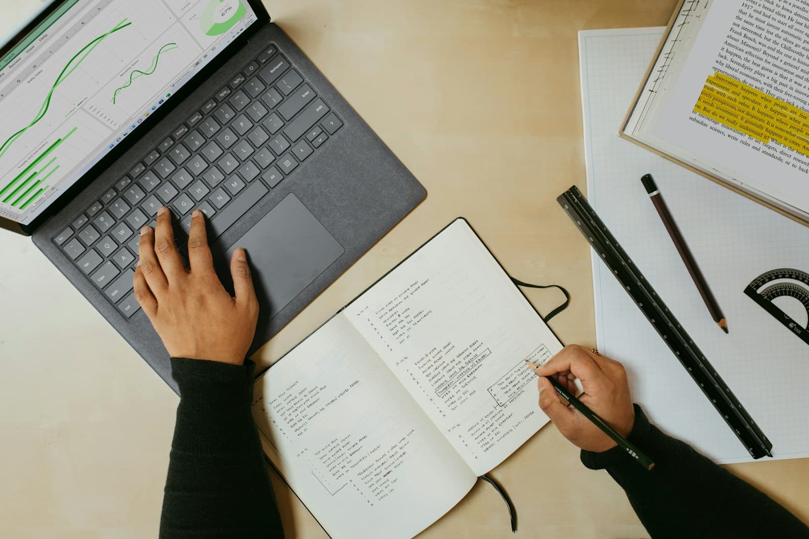 Someone working on a laptop with a notebook